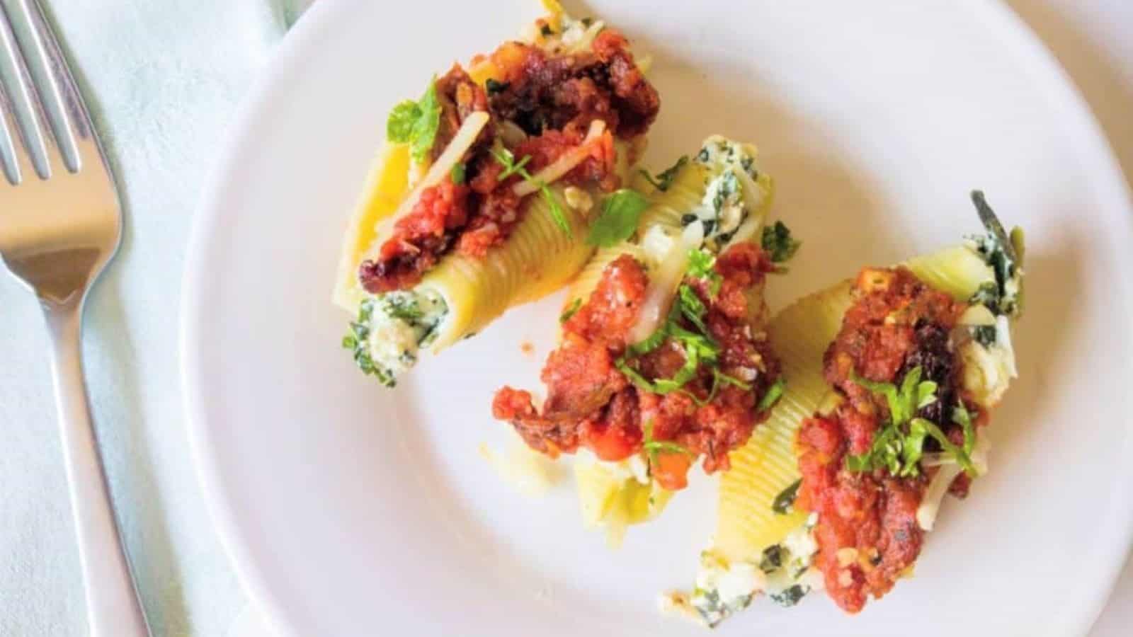 3 stuffed shells on plate with chopped tomatoes.