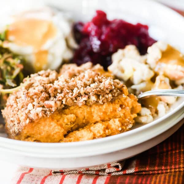 Sweet potato casserole, shredded salad, mashed potatoes with gravy, cranberry sauce, and a poached egg on a plate.