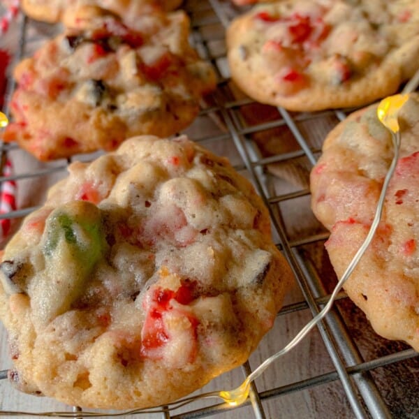 Chunky desserts with red, green, and brown bits sit on a cooling rack next to a string of yellow fairy lights.