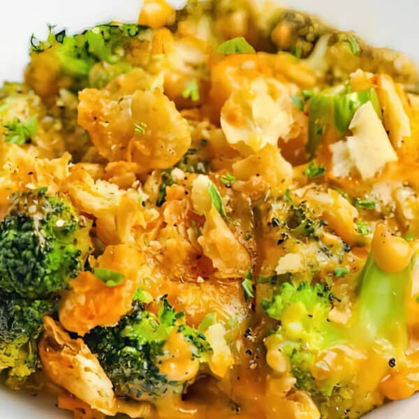 A plate of broccoli florets topped with melted cheese sauce and garnished with herbs.