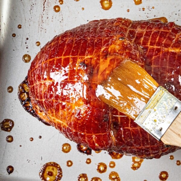 A brush, glaze, baked ham, metal baking tray.