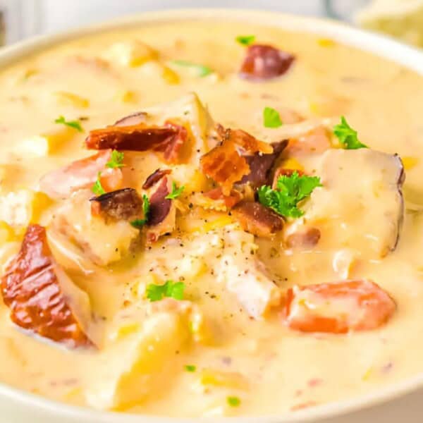 A bowl of potato soup with bacon bits and parsley on top.