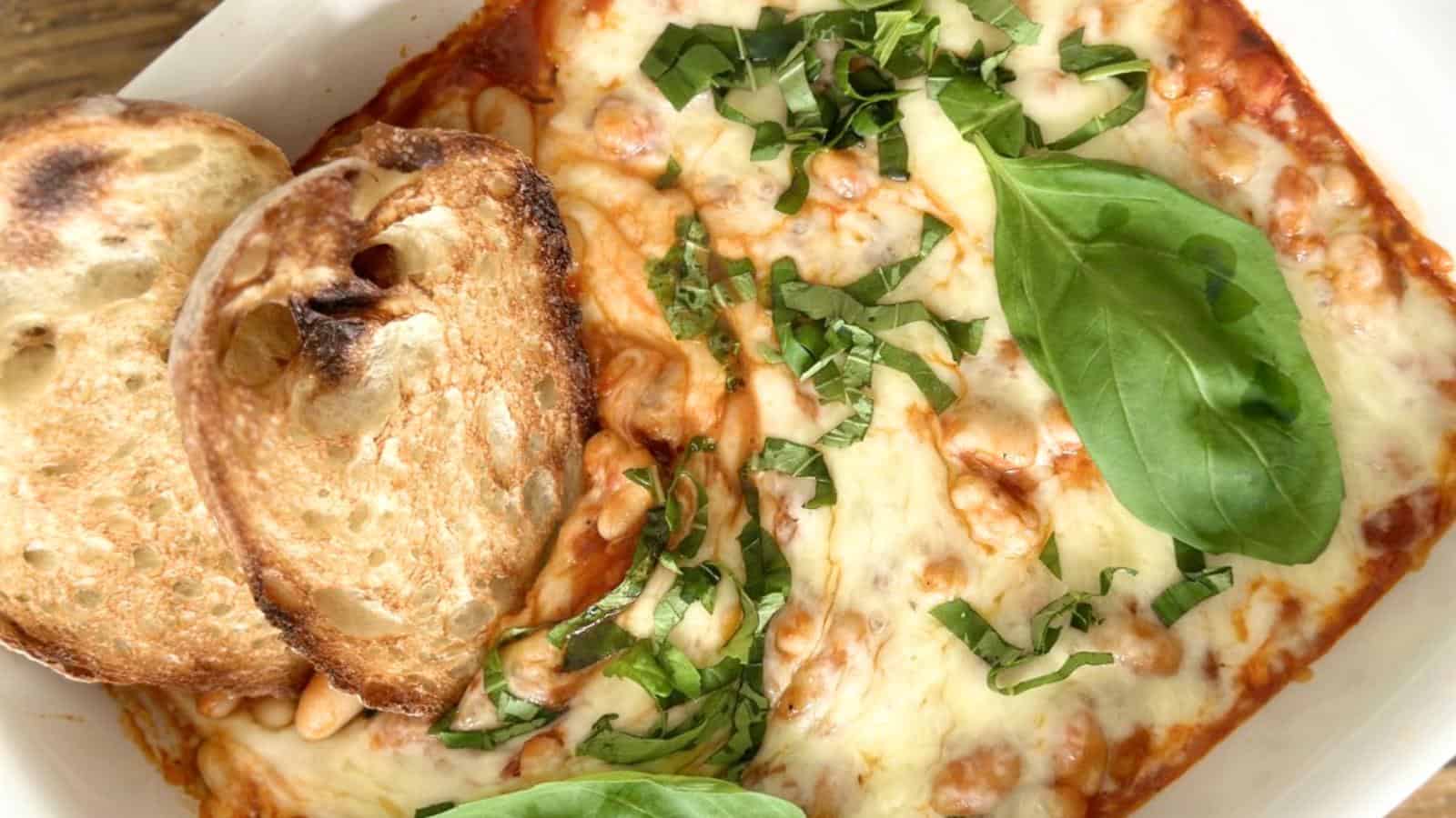 Melted cheese, basil leaves, toasted bread slices.