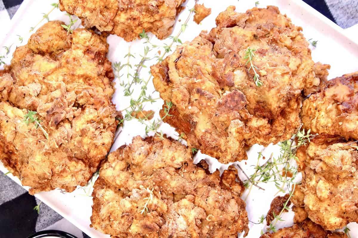 Golden-brown fried chicken pieces with fresh herbs.