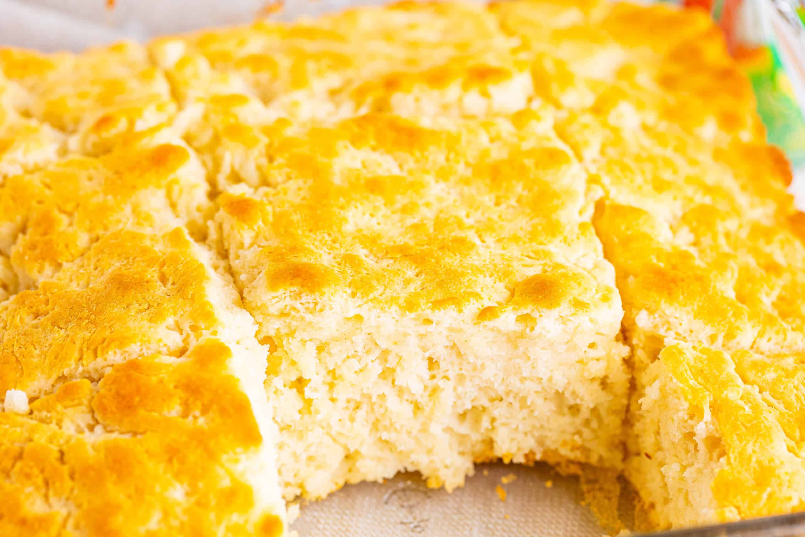 A pan of golden brown baked biscuits with a section showing a soft, fluffy interior.