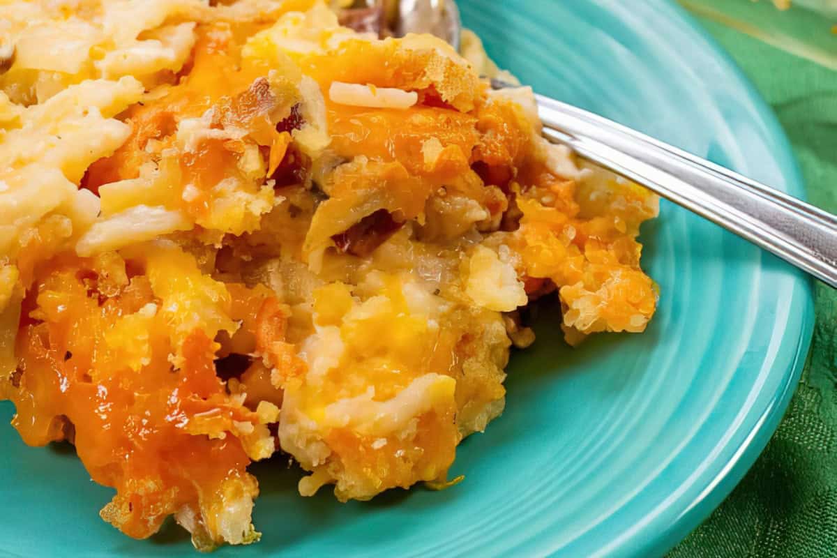 A cheesy potato casserole on a turquoise plate, accompanied by a fork.