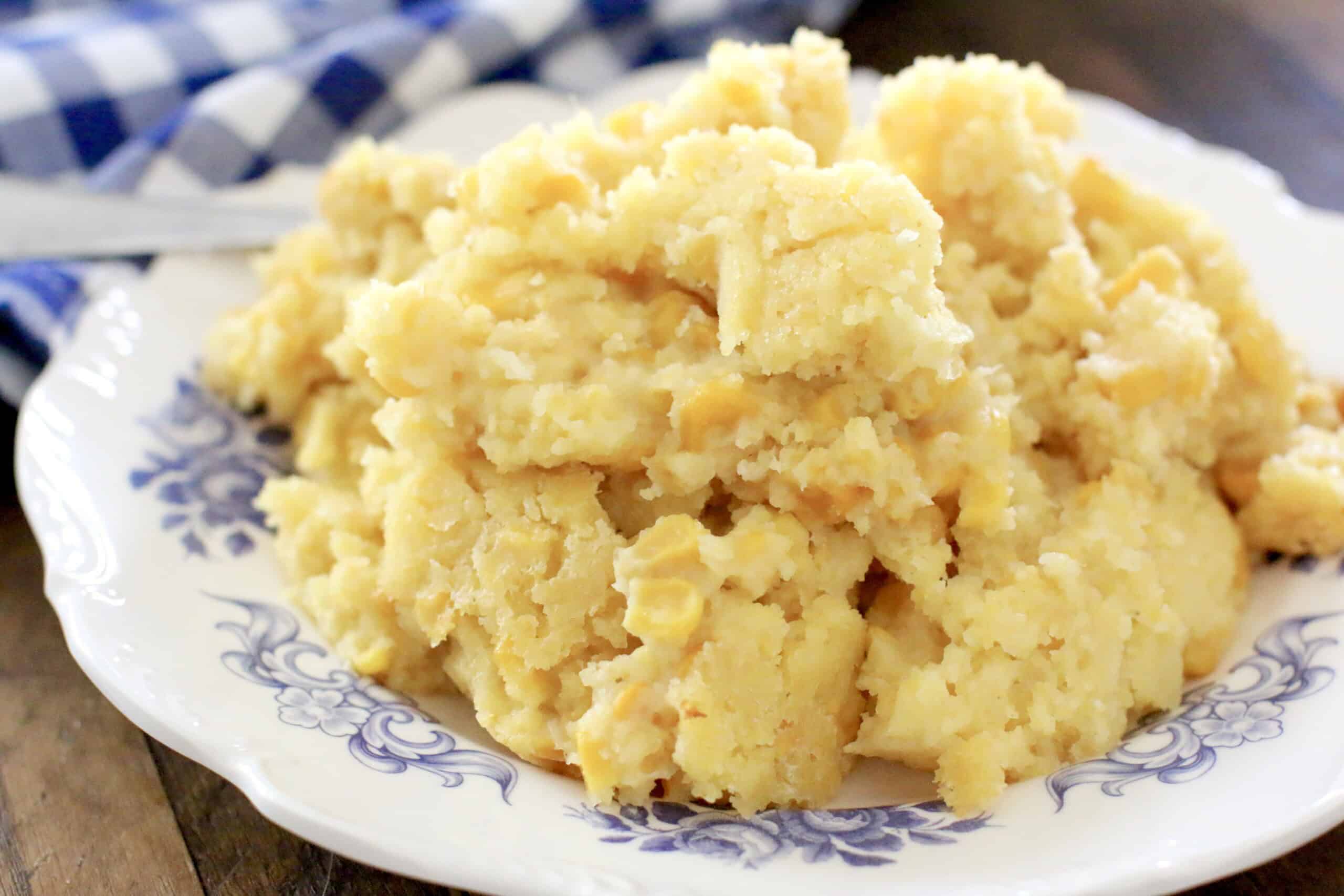 On a plate, there is a mound of mashed potatoes. The background includes a blue and white checkered cloth.