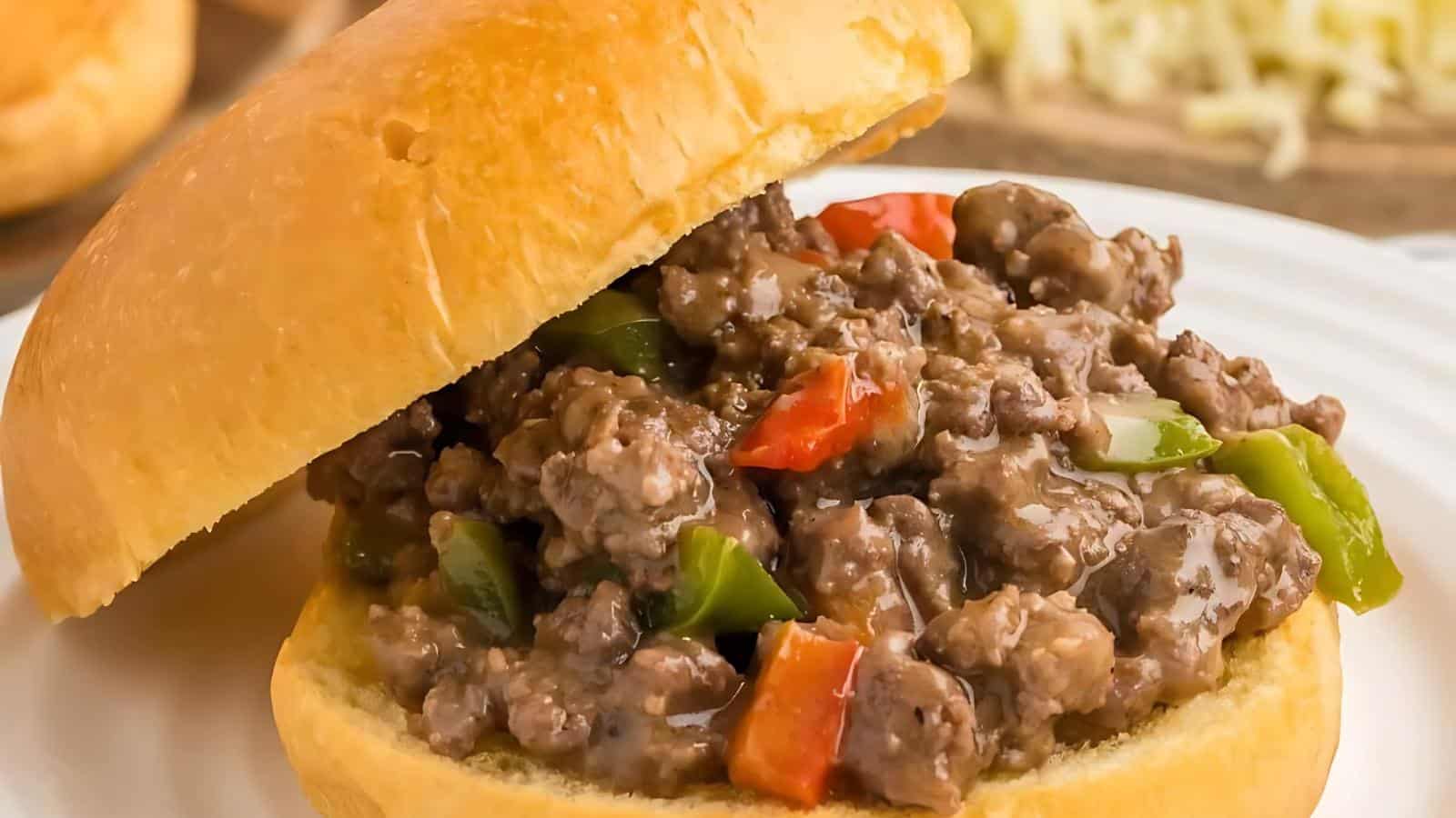 The image shows a sandwich with cooked ground beef, green bell peppers, red bell peppers, and a bun.