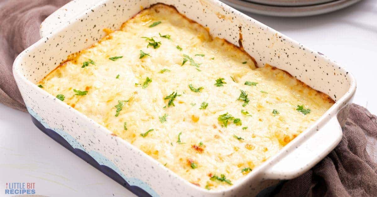 A baked casserole dish with a golden, cheesy topping and fresh parsley garnish.