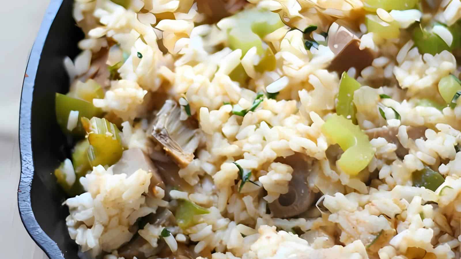 The image shows a close-up of a pan containing cooked rice, chopped green bell peppers, mushrooms, and herbs.