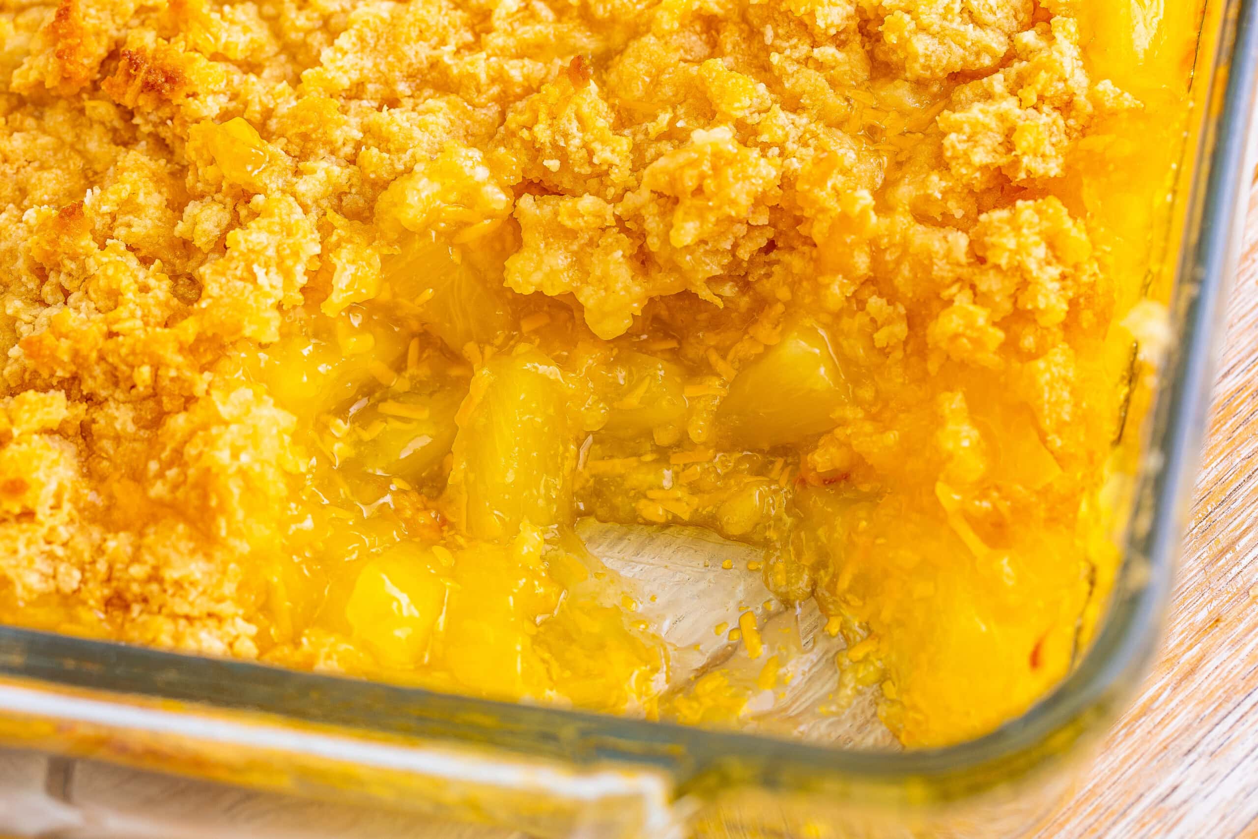 A baking dish with partially eaten peach cobbler, topped with a golden-brown crumb crust.