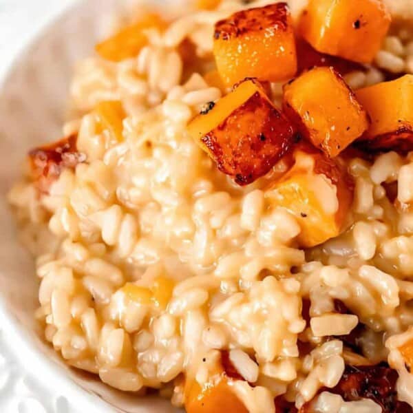 Close-up of creamy risotto with roasted butternut squash cubes served in a white bowl.