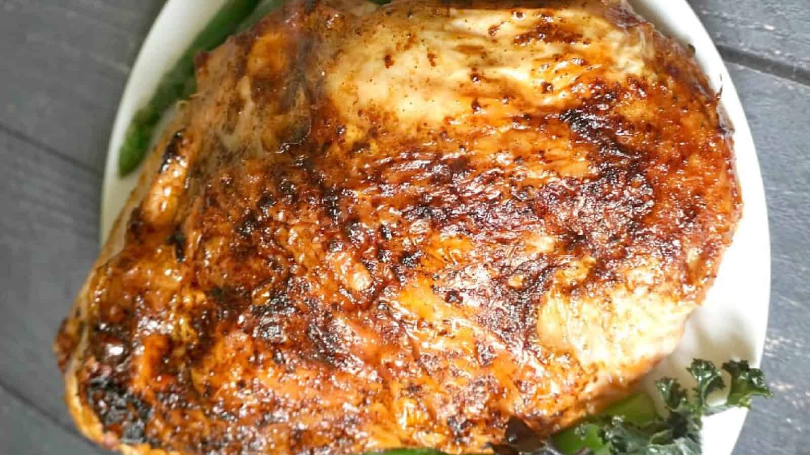 A seasoned, roasted turkey breast on a white plate, garnished with greens.