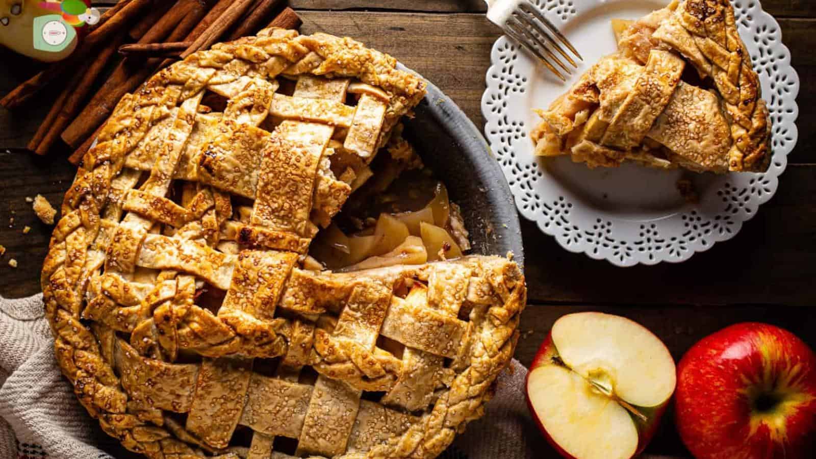 The image features a lattice-topped apple pie in a pan, alongside slices on a plate, two whole apples, and some cinnamon sticks.