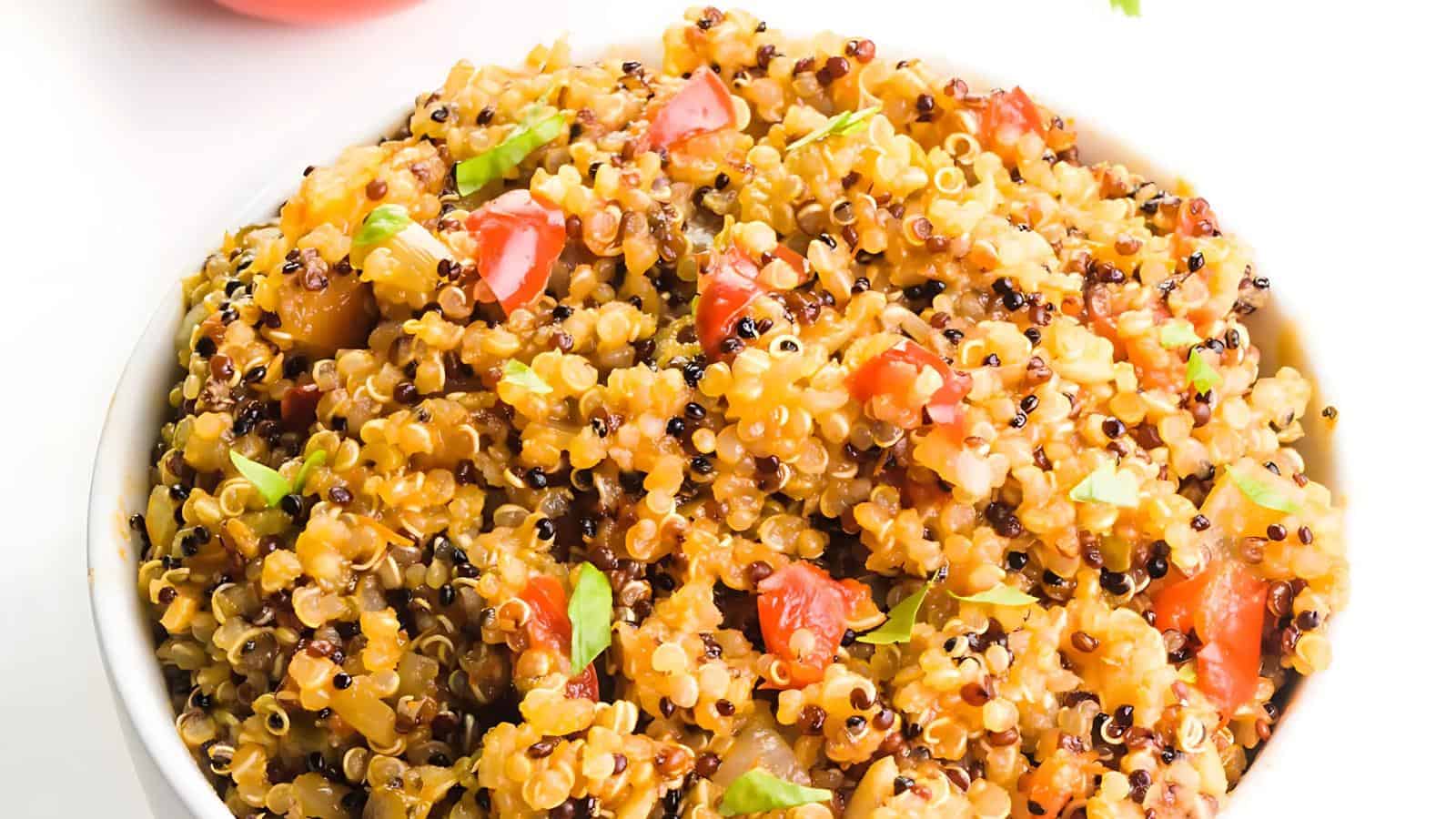 The image shows cooked quinoa mixed with chopped tomatoes and green herbs.