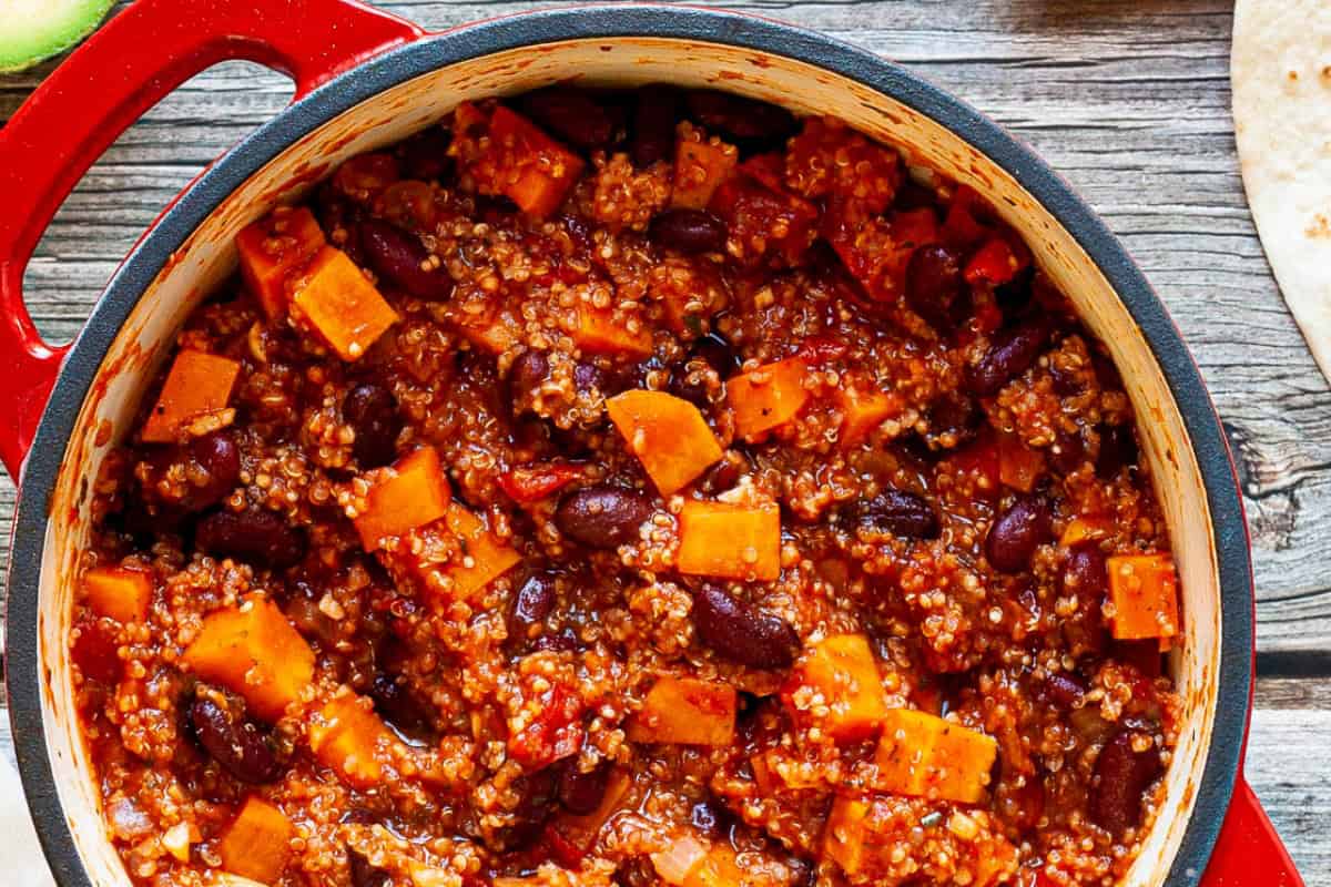 A red dish containing beans, quinoa, and chunks of sweet potato.