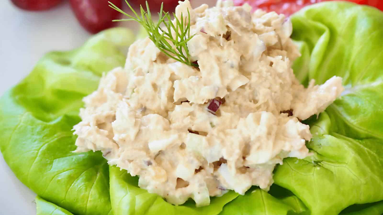 A bed of lettuce topped with chicken salad and garnished with dill.