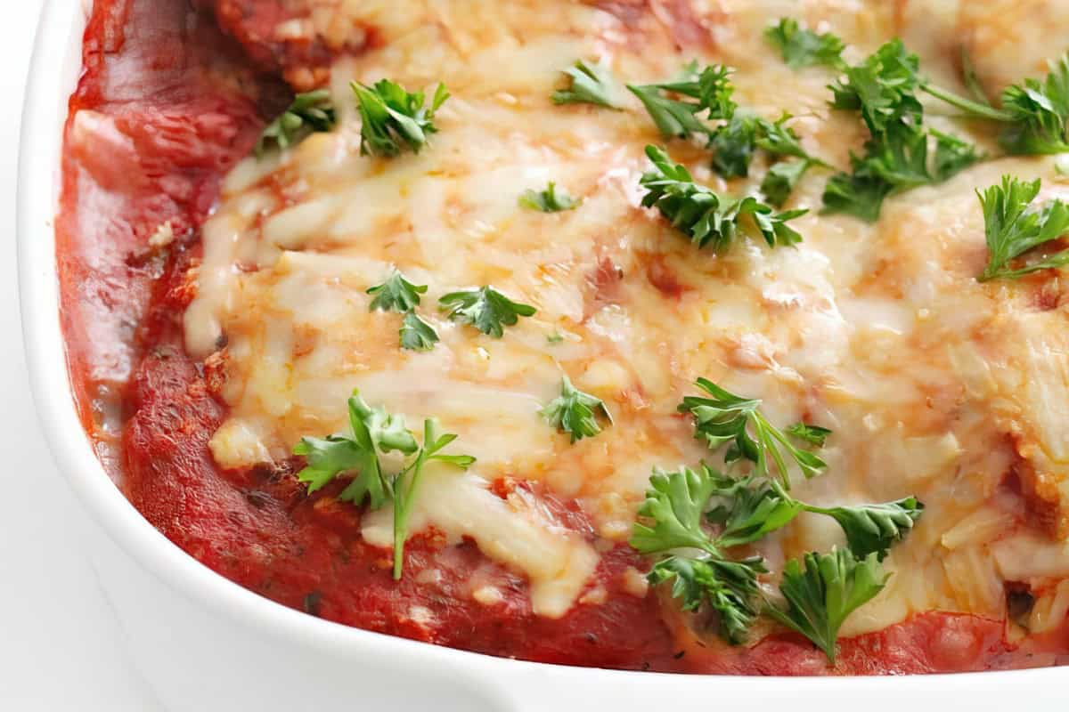 A white dish with melted cheese and fresh parsley on top.