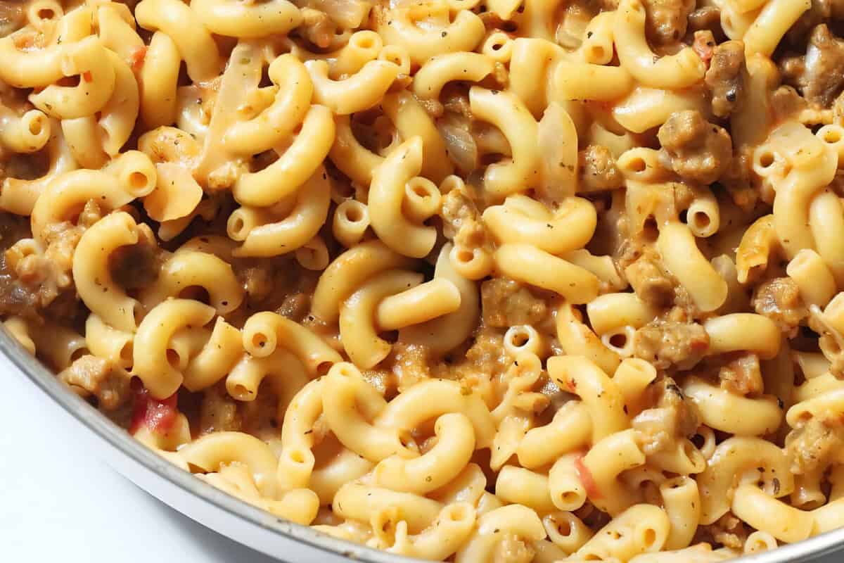 A serving dish filled with creamy macaroni and cheese mixed with ground meat.