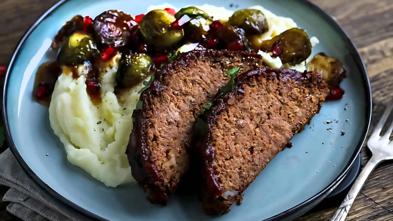 A plate with mashed potatoes, two slices of meatloaf, Brussels sprouts, gravy, and diced red bell peppers.