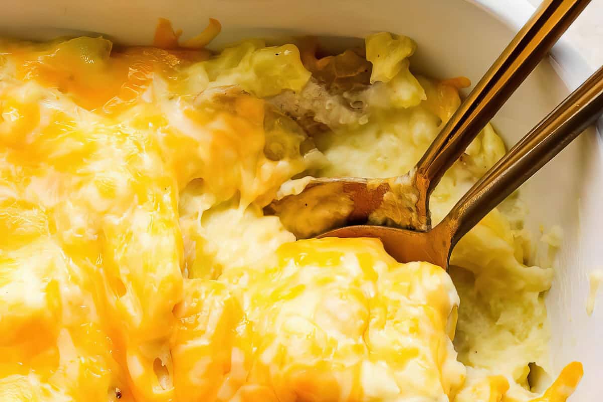 A cheesy casserole dish with two gold spoons.