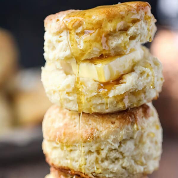 Two stacked biscuits with a slice of butter between them, drizzled with honey.