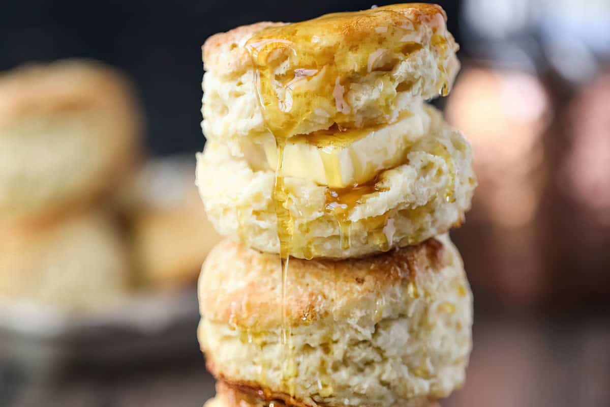 Two stacked biscuits with a slice of butter between them, drizzled with honey.