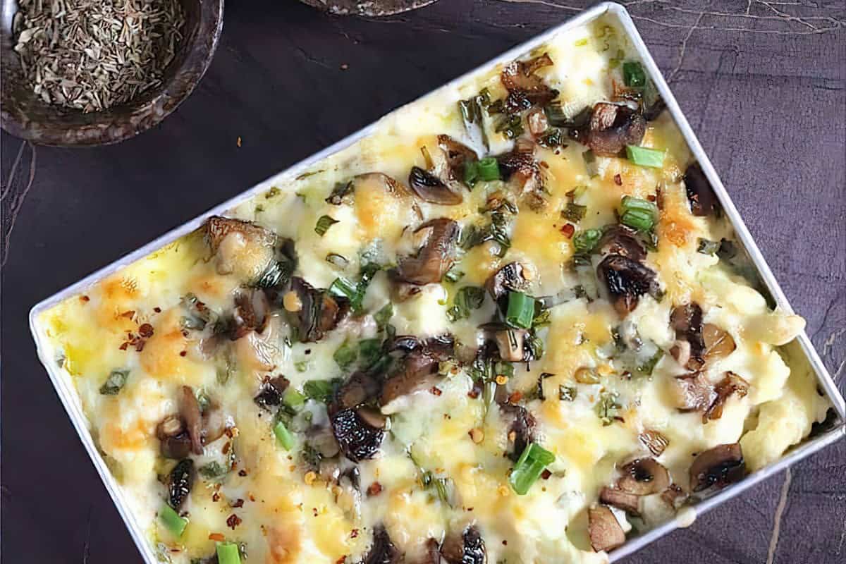A baked casserole featuring melted cheese, mushrooms, and chopped green onions.