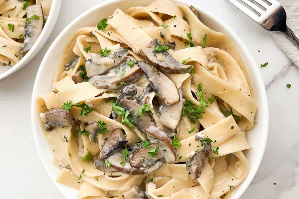 Fettuccine pasta with mushroom sauce and fresh parsley garnish.
