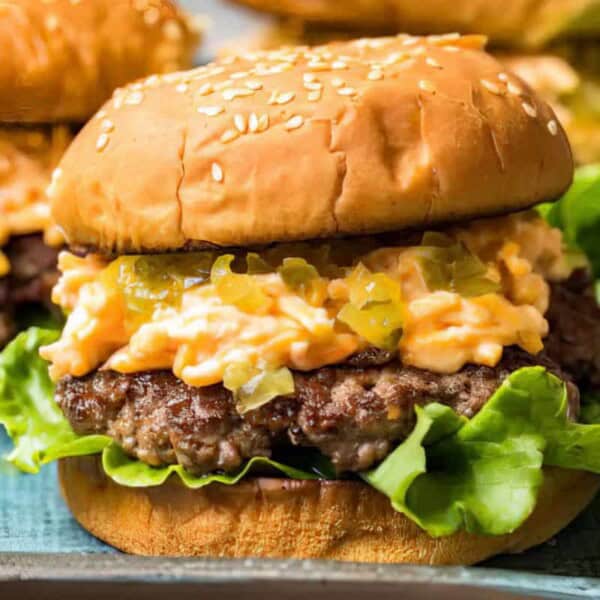 Lettuce, beef patty, melted cheese, relish, and a sesame seed bun in a close-up view of a southern cheeseburger.