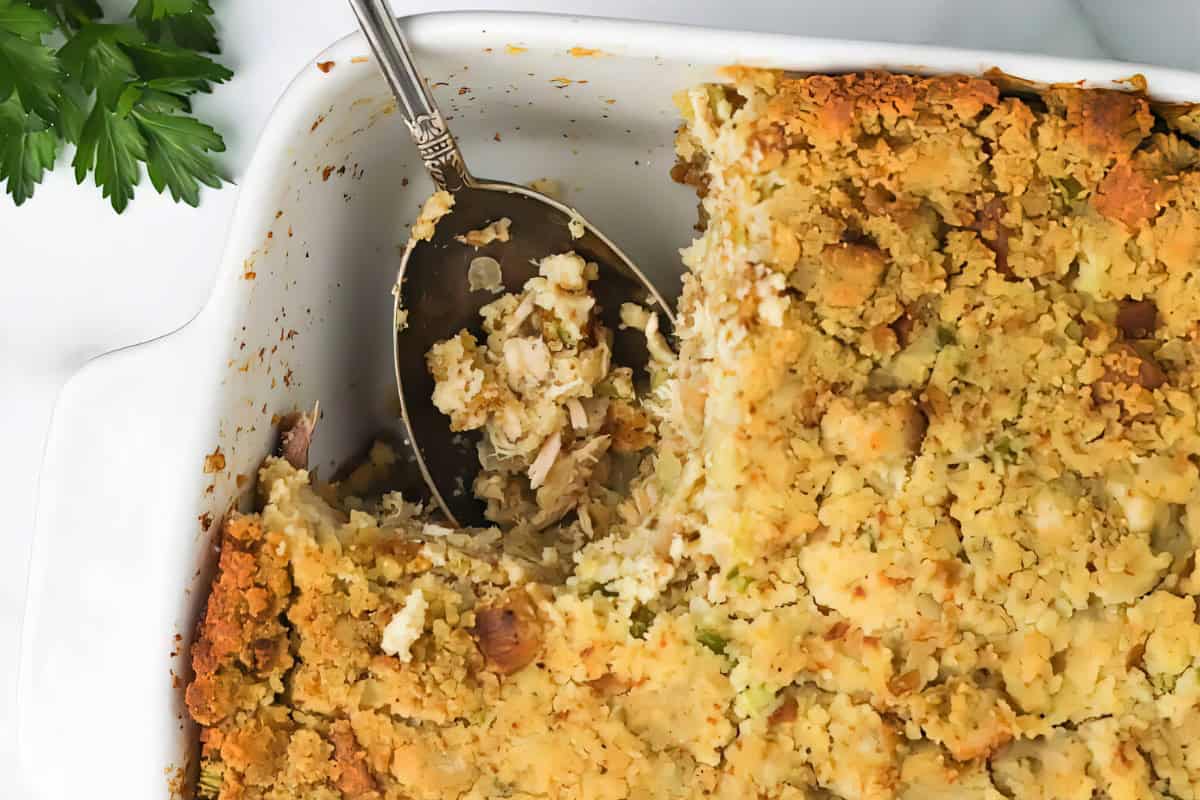 A baked casserole dish with a golden breadcrumb topping and a serving spoon.