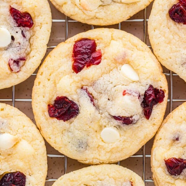 Close-up of cranberry and white chocolate chip cookies cooling on a metal rack.