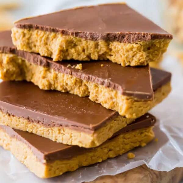 Four bars topped with chocolate are stacked on parchment paper.