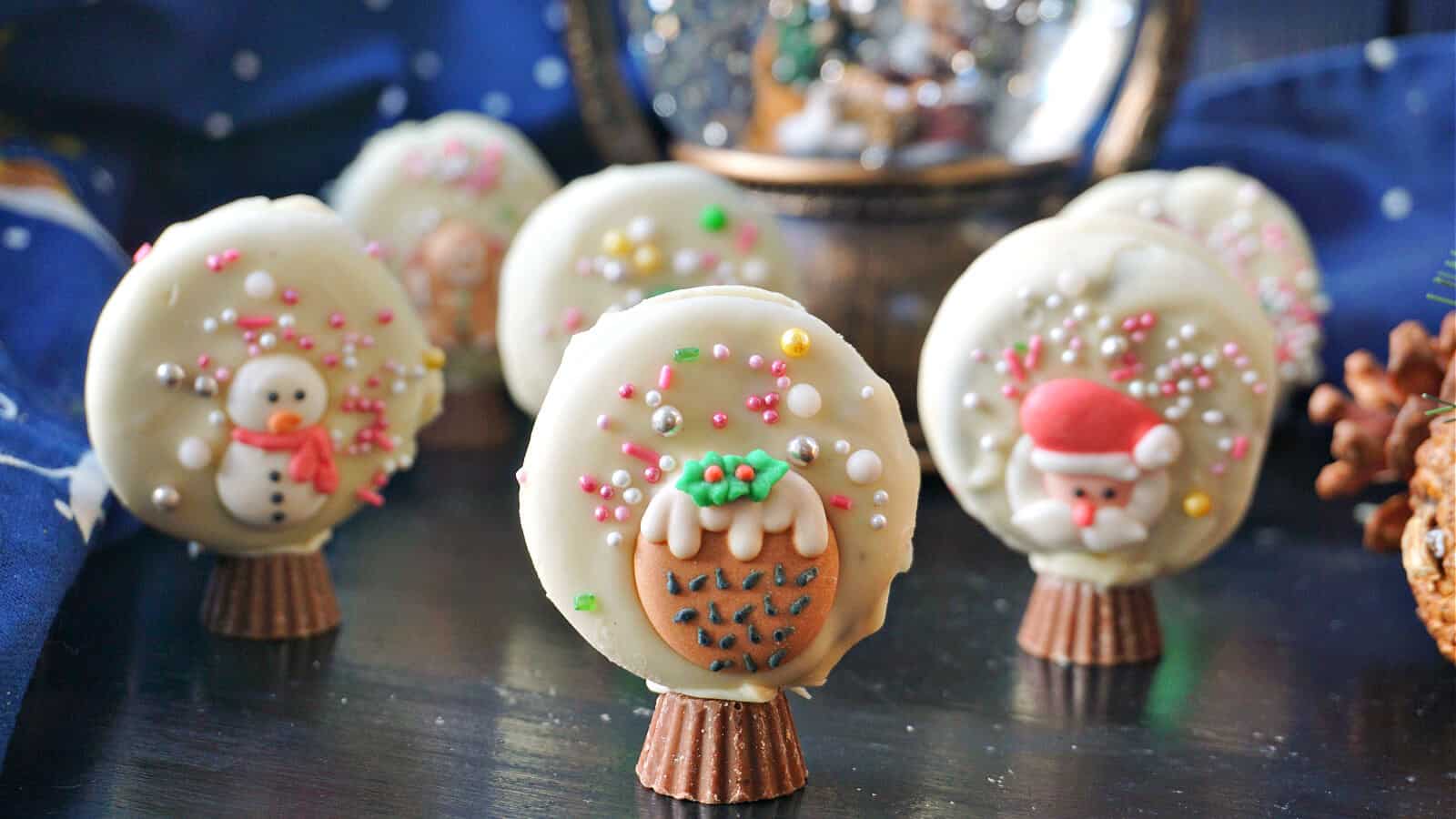 The image features chocolate pops with designs of snowmen, Santa, and holly, standing upright on chocolate bases.