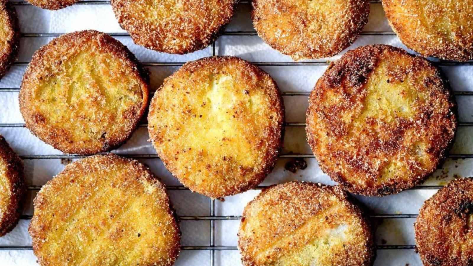 Golden brown, crispy slices of fried green tomatoes cooling on a metal rack.