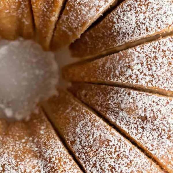 The image features a sliced Bundt cake dusted with powdered sugar, viewed from above.