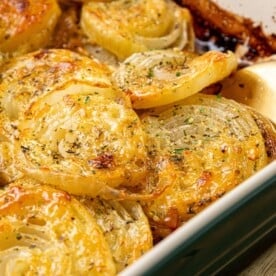 The image features a casserole dish filled with baked, seasoned potato slices and Tennessee onions, topped with a golden-brown crust. A wooden spoon is partially visible on the right side.