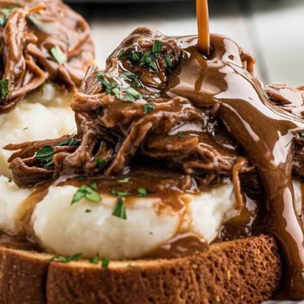 The image shows an open-faced sandwich with slices of bread topped with mashed potatoes, beef, and gravy.