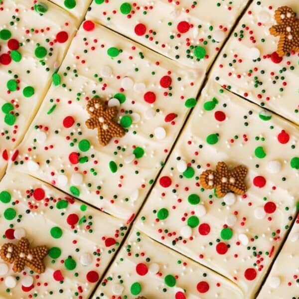 The image features rows of white fudge adorned with red, green, and white sprinkles and small gingerbread figures.