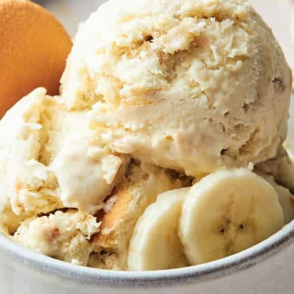 A bowl containing banana pudding ice cream, topped with vanilla wafers and banana slices.