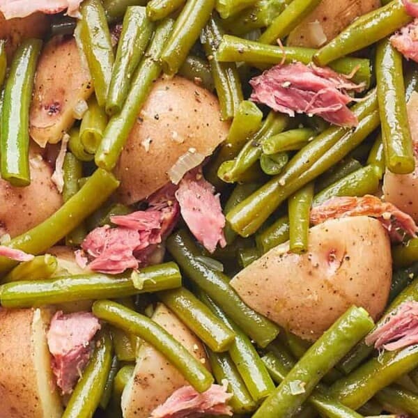 A white plate with southern-style green beans, halved potatoes, and shredded meat.