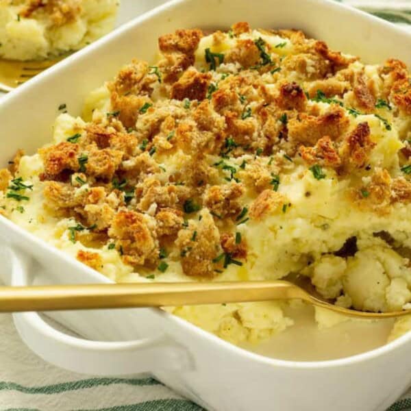 A creamy casserole topped with golden, crispy breadcrumbs and garnished with chopped chives, served in a white dish.