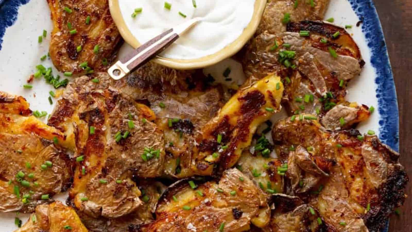 A plate of golden-brown grilled meat sprinkled with chives, served with a side of creamy dipping sauce.
