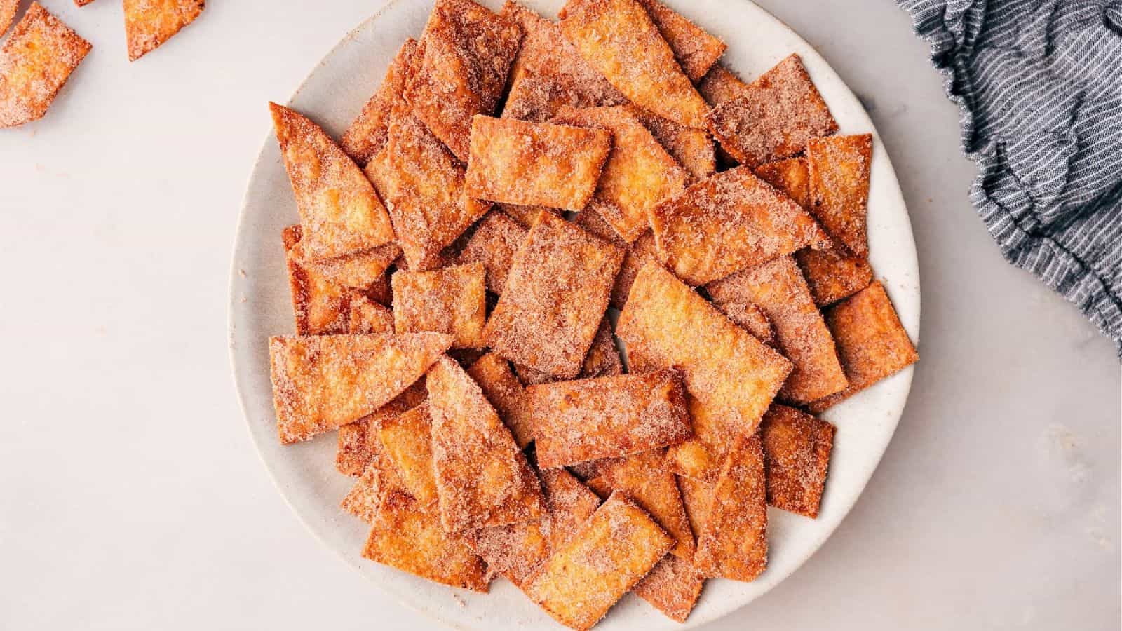 A plate overflowing with crispy, golden-brown cinnamon-sugar tortilla chips, arranged artfully and ready to enjoy.