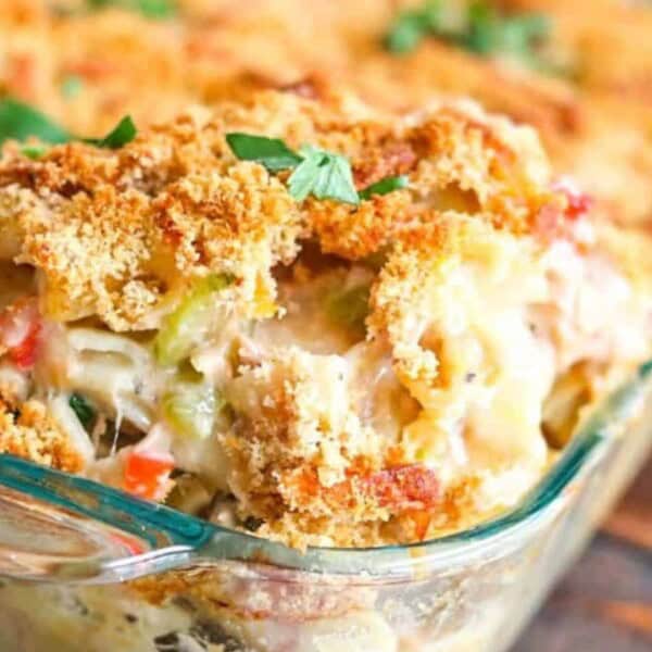 Creamy chicken casserole topped with golden breadcrumbs and parsley, served in a glass dish on a rustic wooden table.