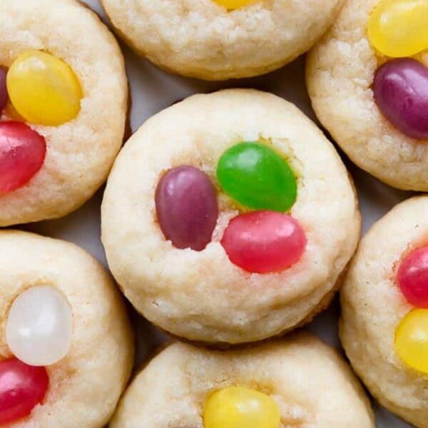 Close-up of cookies topped with colorful jelly beans in yellow, purple, green, and pink, arranged in a neat pattern.