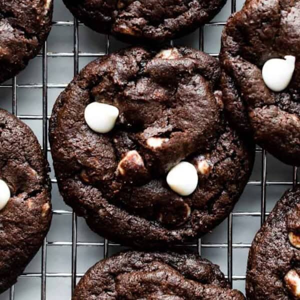 Chocolate cookies with white chocolate chips are resting on a wire rack.