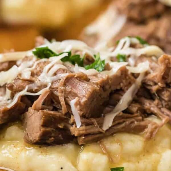 A slice of bread topped with mashed potatoes, shredded beef, grated cheese, and parsley. Served with