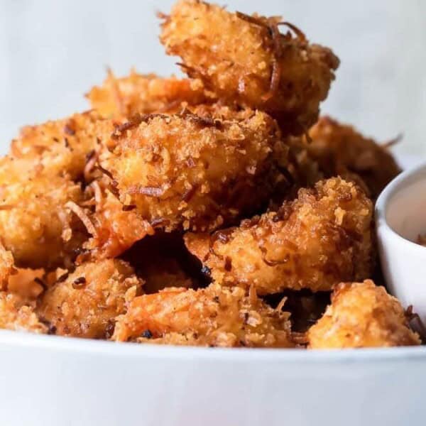 The image features a bowl of crispy fried coconut shrimp accompanied by a small dish of dipping sauce.