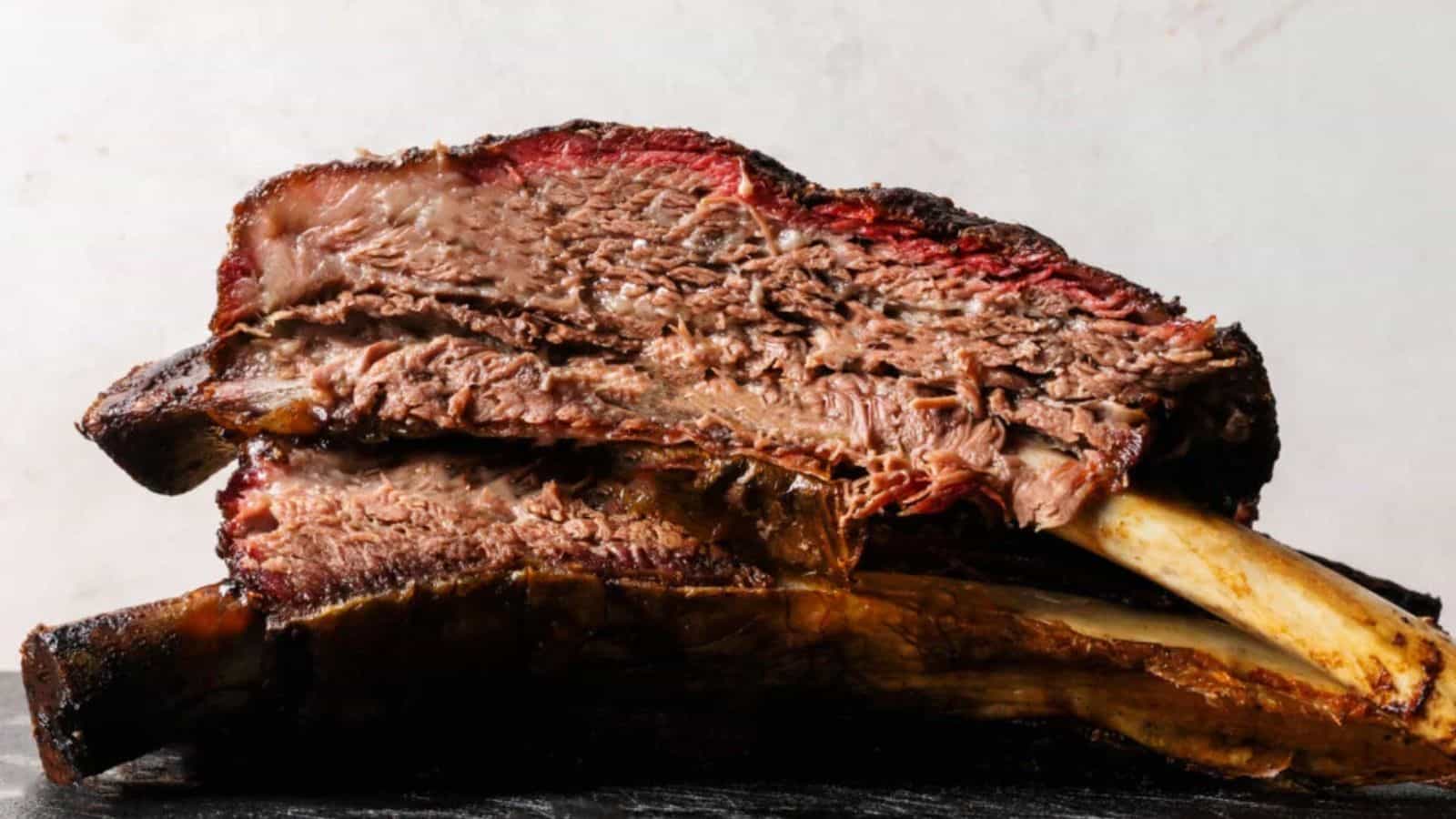 Two large cooked beef ribs stacked on top of each other, with a dark crust and visible juicy interior.